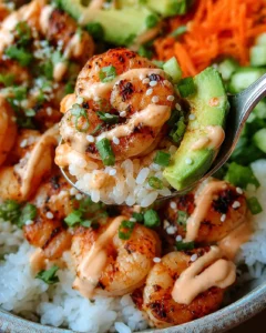 Colorful shrimp rice bowls topped with spicy mayo, avocado, cucumber, and shredded carrots.