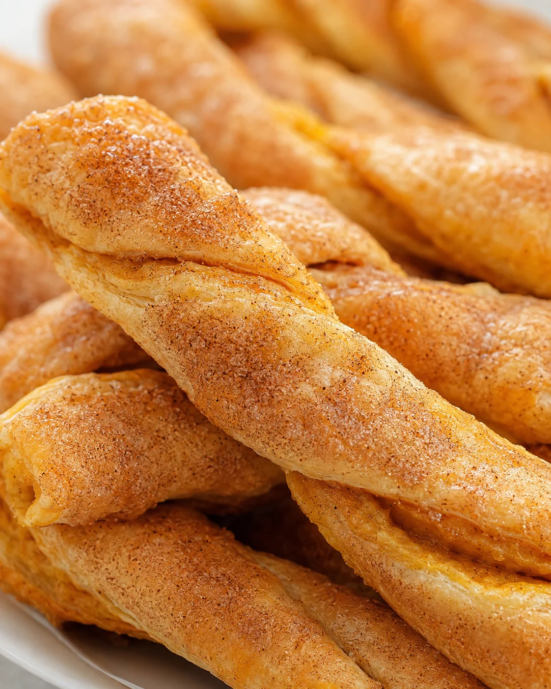Close-up of golden, cinnamon-sprinkled pumpkin pie twists on a plate