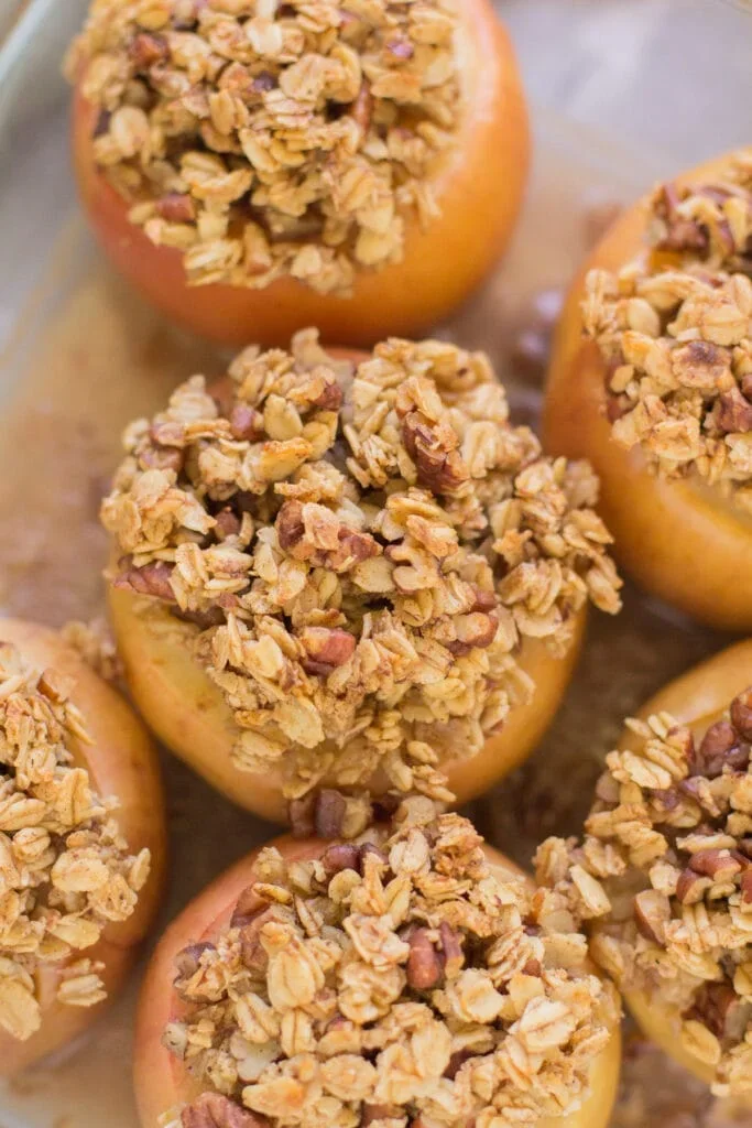 Top-down ingredients for healthy baked apples including apples, oats, pecans, cinnamon, and maple syrup